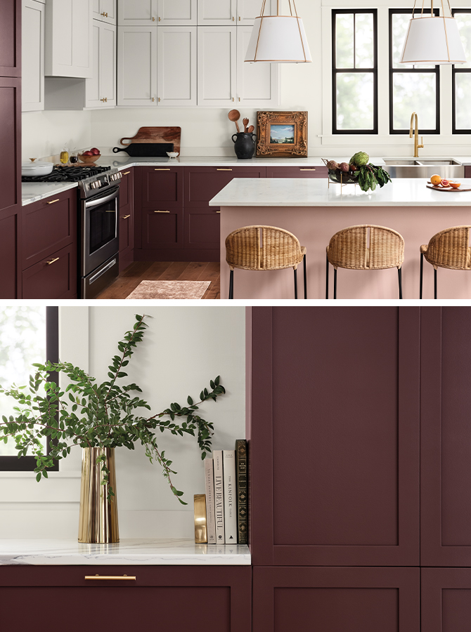 Brightly lit modern kitchen with marble countertops, center island painted pink, dark purplish red lower perimeter cabinets and white upper cabinets with bright metal hardware.
