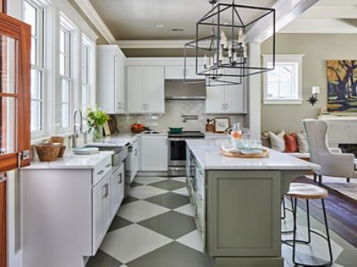 A modern kitchen with white cabinets and countertops, olive green island, and painted checkerboard floors.