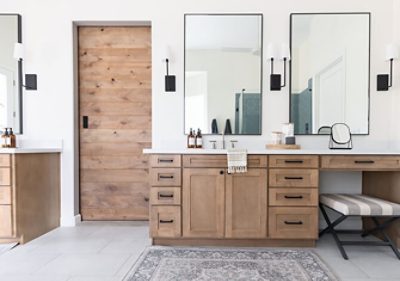 Double bathroom vanity with natural wood cabinetry, large rectangular mirrors and modern fixtures.