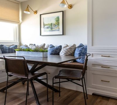 Close shot of banquette dining area with under-bench storage, throw pillows in various patterns, and removable chairs for wheelchair access.