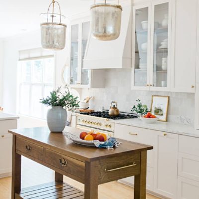 Warm white kitchen with natural wood island and European-inspired cabinetry and appliances.