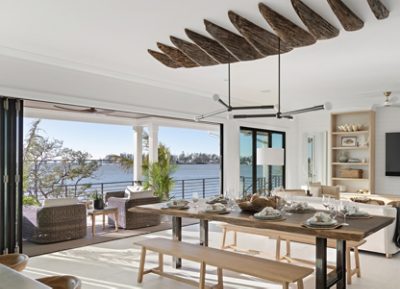 Open-concept dining and living area with Pure White walls and trim, wooden ceiling detail, a waterfront view, and modern furnishings.