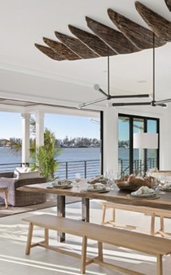 Open-concept dining and living area with Pure White walls and trim, wooden ceiling detail, a waterfront view, and modern furnishings.