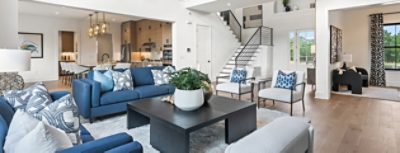 Modern living room with blue sofas, square coffee table, open kitchen, and staircase in the background featuring walls painted Pure White by Sherwin-Williams.