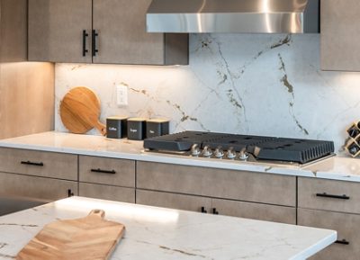 Modern kitchen with a marble-look quartz countertop, black-labeled canisters, a wooden cutting board, and a stainless steel stove.