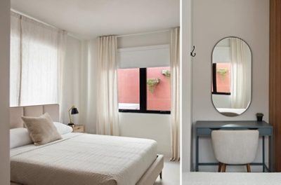 A serene and minimal modern bedroom with a bed, curtains, and a vanity with rounded mirror. 