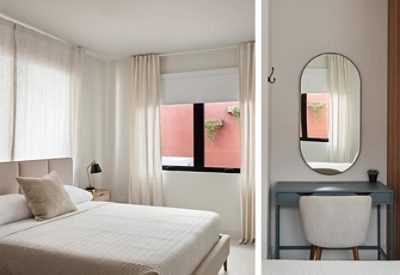 A serene and minimal modern bedroom with a bed, curtains, and a vanity with rounded mirror. 