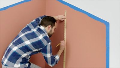 A man marking a wall with a ruler