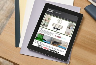 Electronic tablet on top of large-sized color samples on a wooden desktop with the Design Education Center webpage featured on screen.