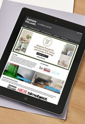 Electronic tablet on top of large-sized color samples on a wooden desktop with the Design Education Center webpage featured on screen.