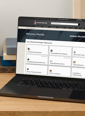 An open laptop and Sherwin-Williams color tools on a wooden desktop with the Design+ dashboard featured on screen.