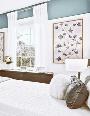 Bedroom with a white bedspread, fireplace, large window, and decorative accents in blue and wBedroom with a white bedspread, fireplace, large window, and decorative accents in blue and white, featuring Sherwin-Williams Morning at Sea and Stargazer.hite, featuring Sherwin-Williams Morning at Sea and Stargazer.