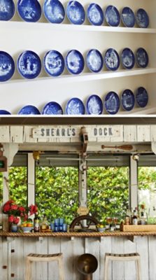 A collection of blue decorative plates on white shelves and a rustic outdoor home bar with nautical decor.