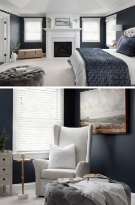 Bedroom showing king bed with tufted headboard, vaulted white ceilings and fireplace, dark charcoal walls, and armchair in corner.