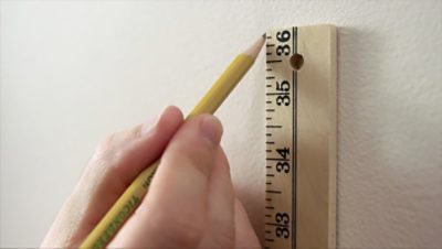 A man marking a wall with a ruler