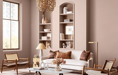 A neutral living room with midcentury modern furniture and pink-tan walls with built in shelves.