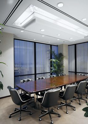 An office meeting room with a long wooden table, chairs, plants and floor to ceiling windows.