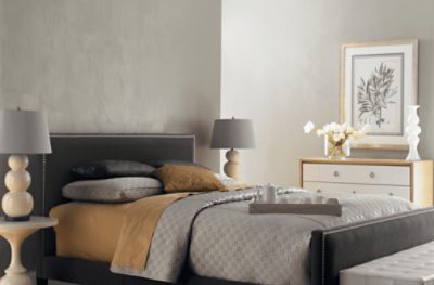 A bedroom with gray walls and some bronze textile accents.