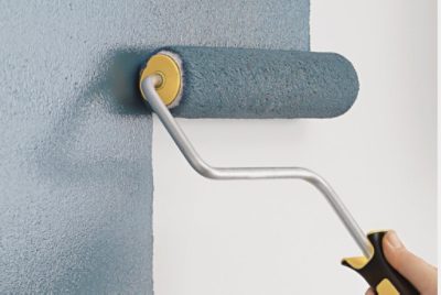 A person painting a wall using a paint roller.