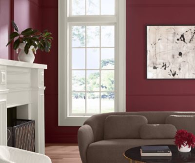 Living room painted in SW 7578 Borscht, brown couch, white fireplace, window, minimal decor.