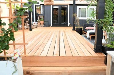 A new lightly stained walk out deck with patio furniture and plants.