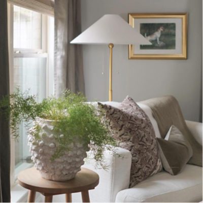Living room painted in morning fog with neutral loveseat, plant, lamp, and picture frame, by @stayhomestyle_.