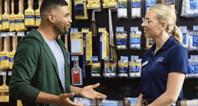 A painter talking to a Sherwin-Williams employee in front of rollers and roller covers.