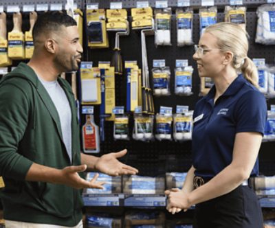 A painter talking to a Sherwin-Williams employee in front of rollers and roller covers.