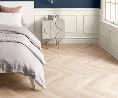 A bedroom with wood floors and white wainscotting.