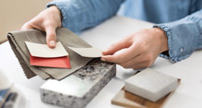 A person comparing paint, textile and stone swatches.