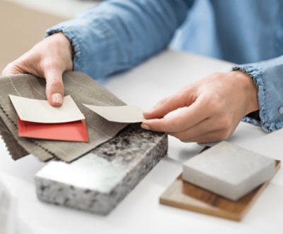 A person comparing paint, textile and stone swatches.