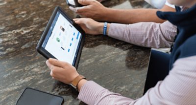 A person shopping on an iPad and another on a phone.