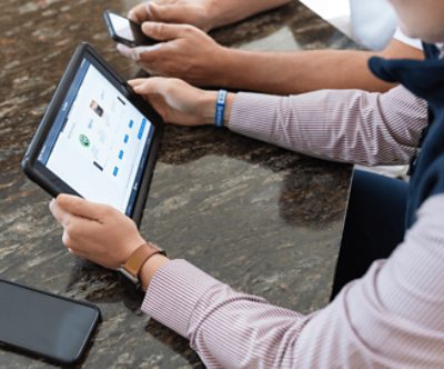 A person shopping on an iPad and another on a phone.