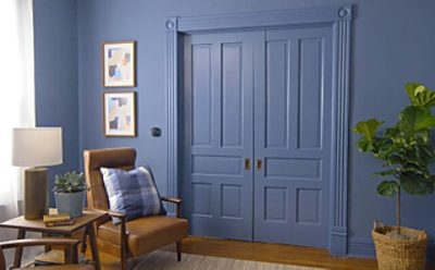 A living room with dark blue walls and a set of two sheen doors..