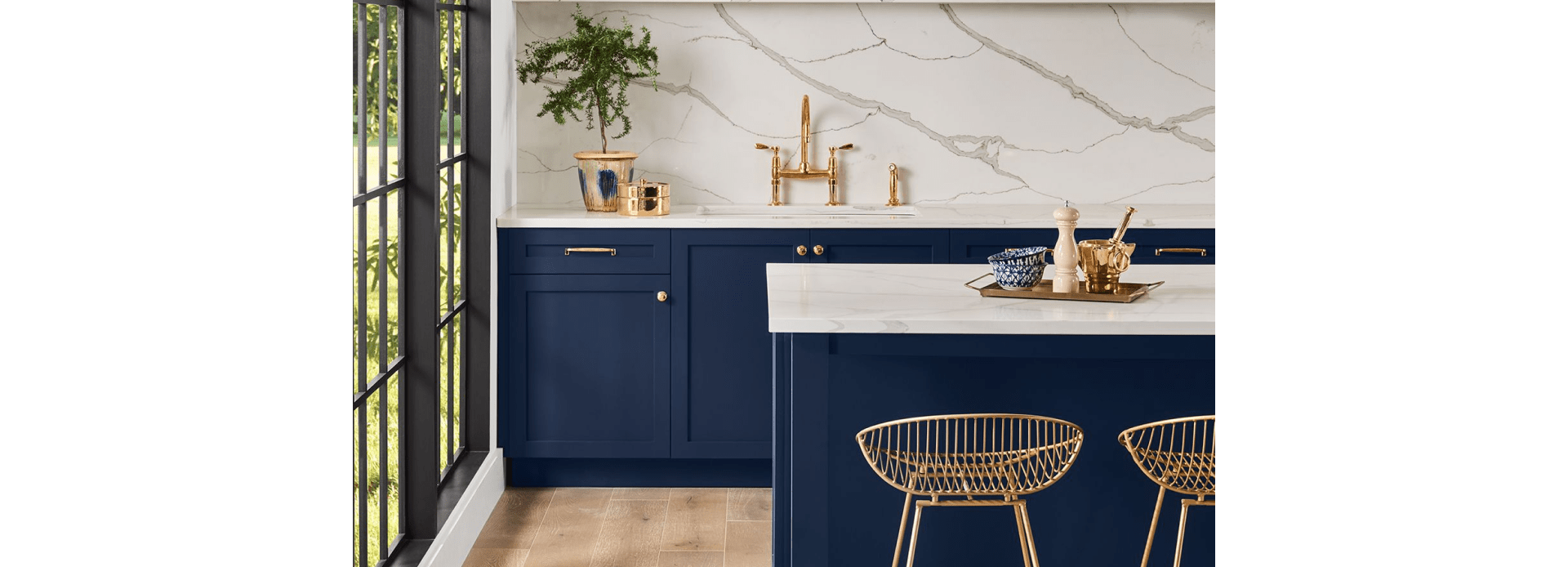 Kitchen with Sherwin Williams 2020 Color of the Year Naval SW 6244 painted cabinets and island, white marble backsplash, and gold accents. 