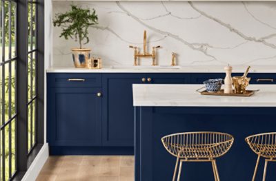 Kitchen with Sherwin Williams 2020 Color of the Year Naval SW 6244 painted cabinets and island, white marble backsplash, and gold accents. 