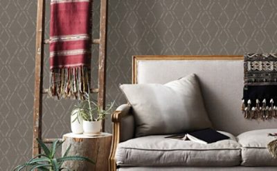 A bedroom with a sofa and a neutral and rustic wallpaper design.