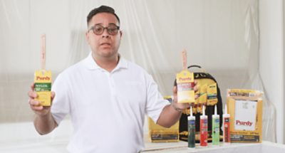 A person holding two Purdy brushes.