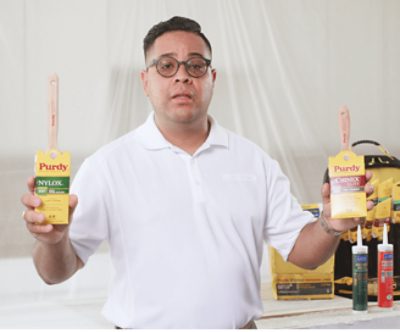 A person holding two Purdy brushes.