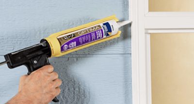 A person caulking a window.