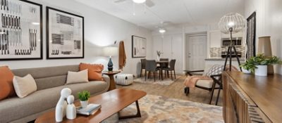 A modern living room and dining area inside an apartment with neutral toned decor, Repose Gray walls, and abstract artwork.