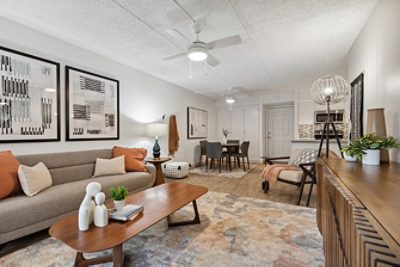 A modern living room and dining area inside an apartment with neutral toned decor, Repose Gray walls, and abstract artwork.