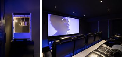 Dark home theater room with popcorn machine and leather theater chairs in two rows in front of a large projected image of a man in sunglasses.
