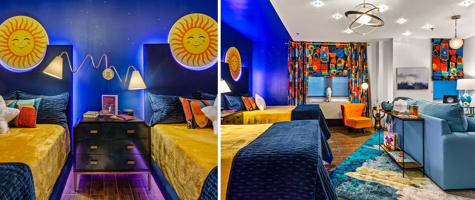 Guestroom in Ronald McDonald House with dark blue walls, funky furnishings, bold patterned curtains and celestial accents like large smiling sun faces above the headboards and star-shaped throw pillows.