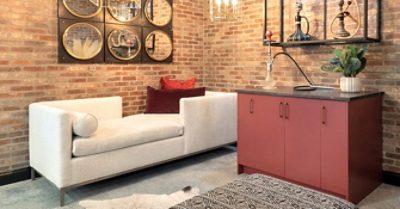 Hookah bar area in basement with mirrored wall art on brick walls, a red painted bar, hookah pipes on display and chaise lounge style seating.