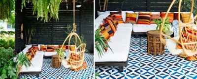 An outdoor seating area with a white sofa, colorful pillows, plants, a wicker chair, and a geometric faux-tile floor painted in Sherwin-Williams Adriatic Sea and In the Navy.