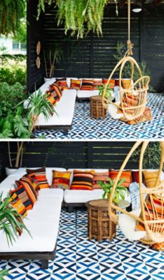 An outdoor seating area with a white sofa, colorful pillows, plants, a wicker chair, and a geometric faux-tile floor painted in Sherwin-Williams Adriatic Sea and In the Navy.