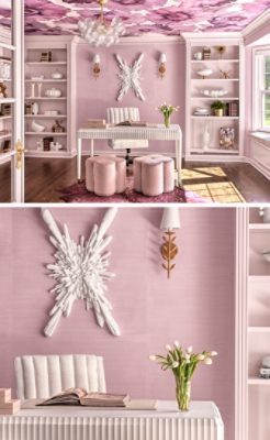 A pastel pink home office with a white fluted desk, pink stools, and bookshelves. A floral wallpapered ceiling and a white starburst wall sculpture add decorative detail.