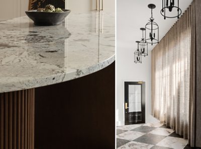 Close-up of the curved kitchen island countertop with a bowl and a room with lantern-style pendant lights, floor-to-ceiling curtains, and marble tile flooring bathed in natural light. 