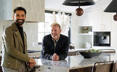 Designer Aly Velji and husband Jason Krell standing at the marble island in their newly renovated kitchen.
